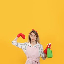 Photo of Young housewife with detergent and sponge on yellow background