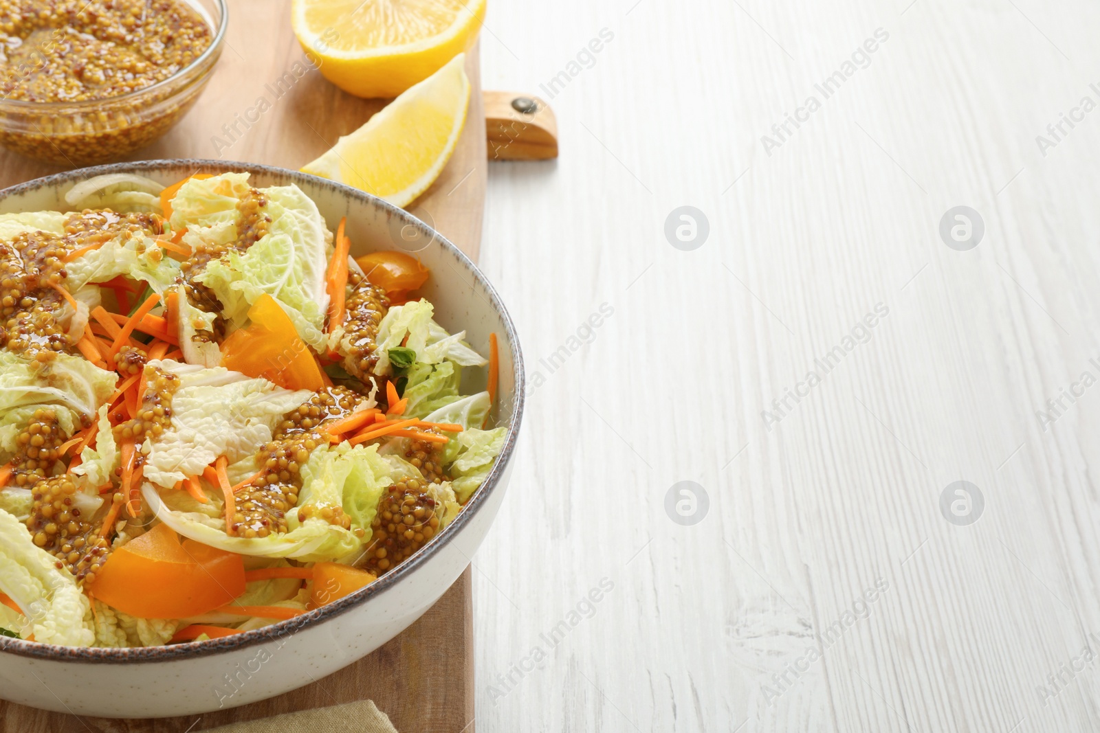 Photo of Delicious salad with Chinese cabbage and mustard seed dressing on white wooden table. Space for text