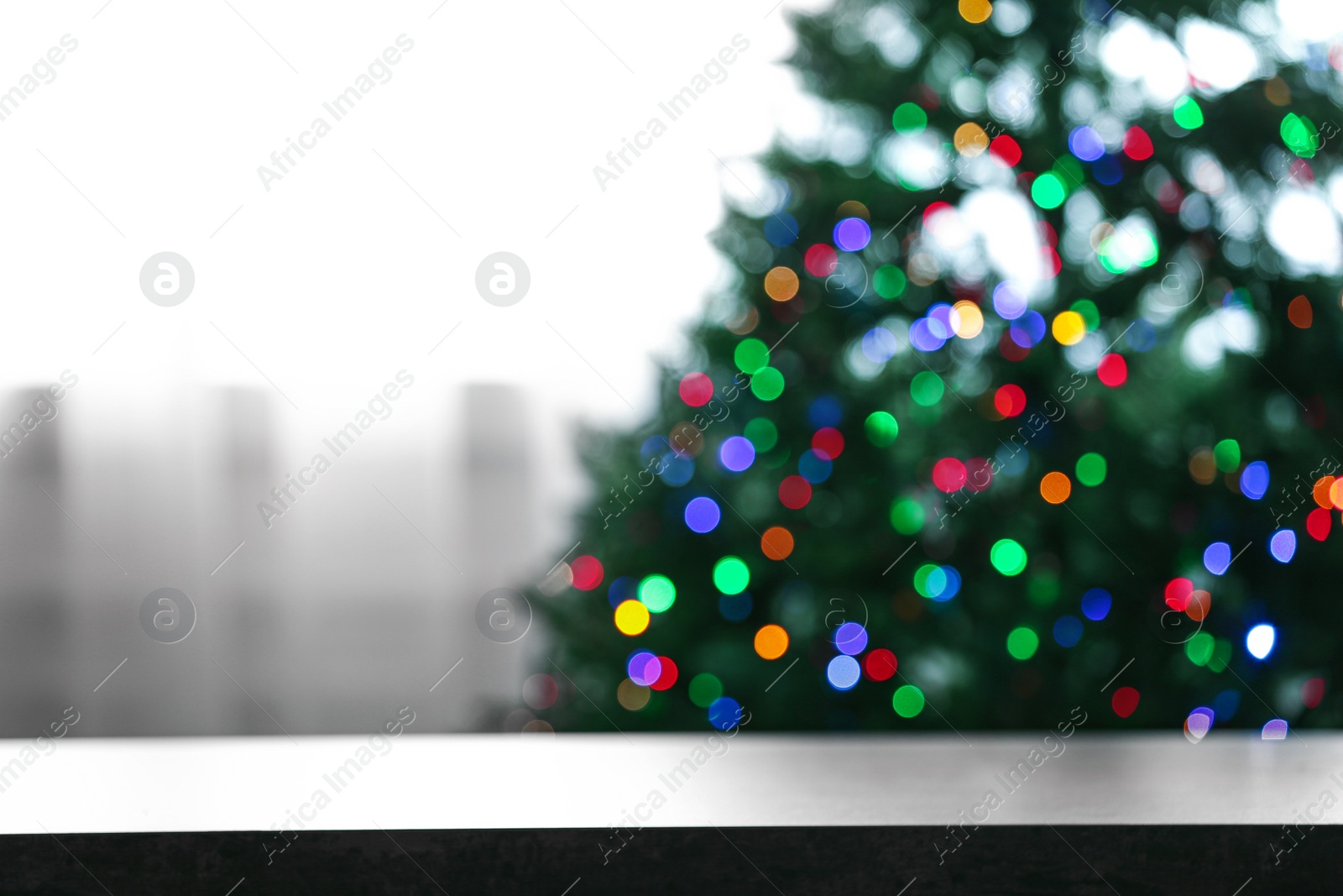 Photo of Empty table and blurred fir tree with colorful Christmas lights on background, bokeh effect. Space for design