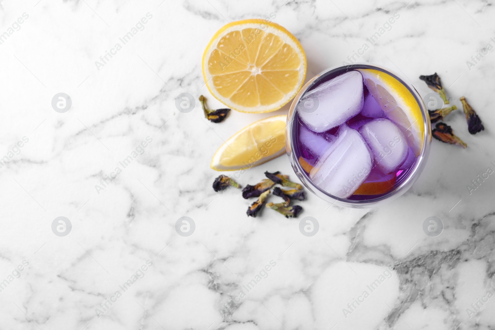 Photo of Top view of organic blue Anchan with lemon and ice on white marble table, space for text. Herbal tea