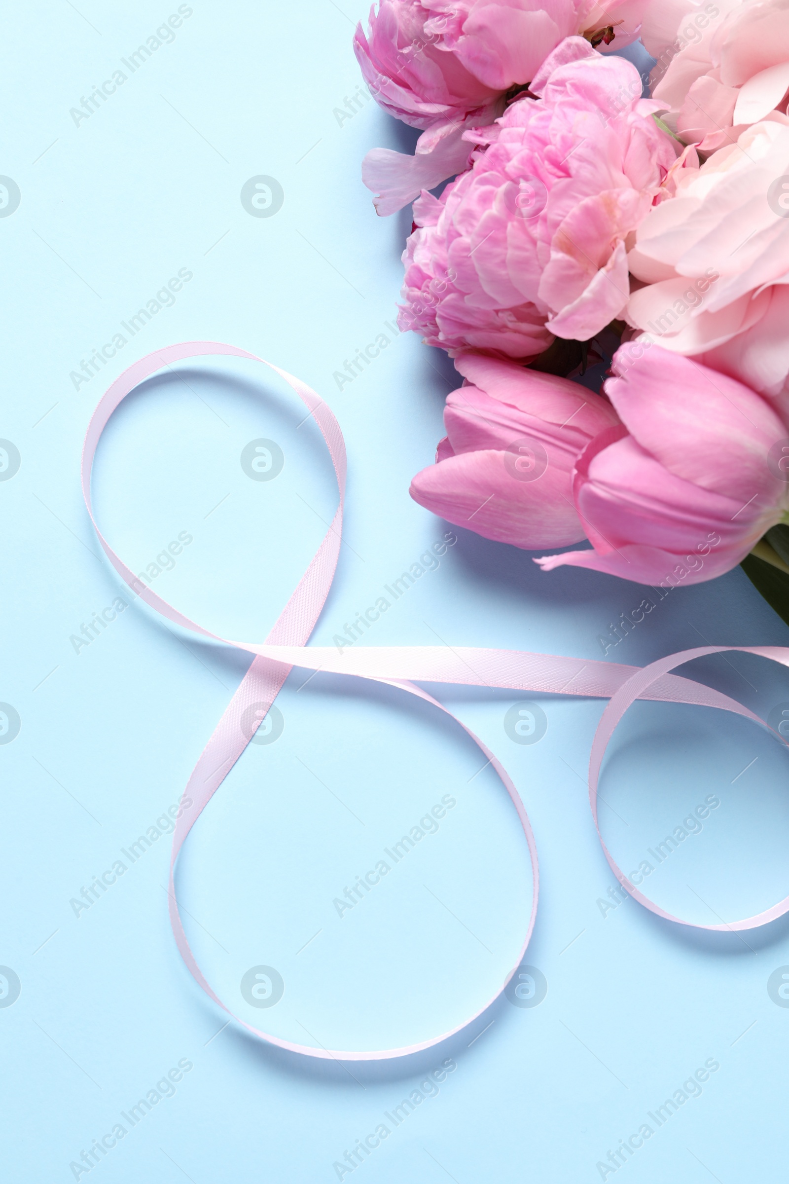 Photo of 8th of March greeting card design with pink ribbon and beautiful flowers on light blue background, flat lay. International Women's day