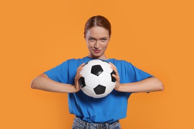 Fan holding football ball on orange background