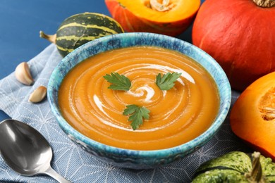 Photo of Delicious pumpkin soup served on blue table, closeup