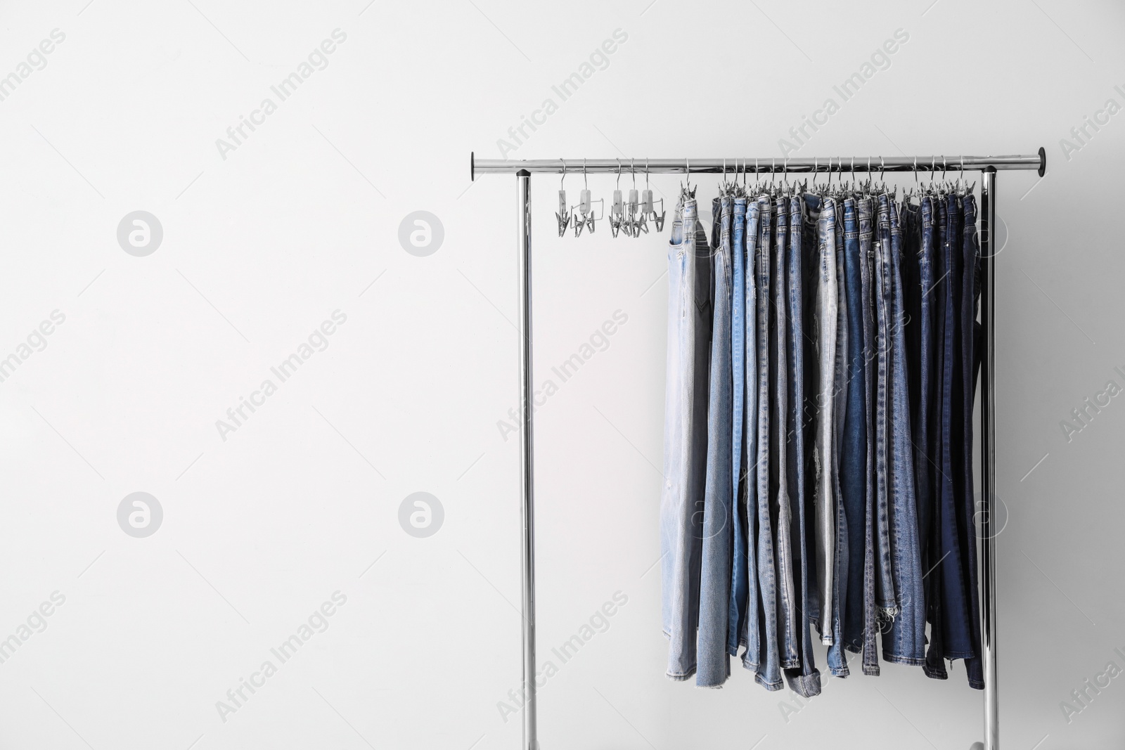Photo of Rack with different jeans on white background. Space for text