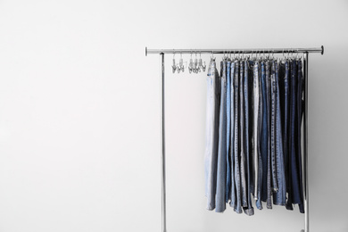 Photo of Rack with different jeans on white background. Space for text