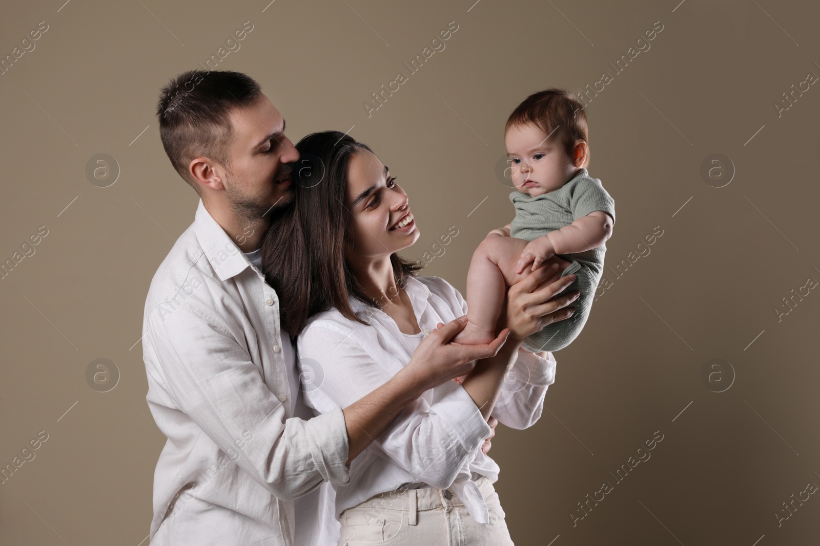 Photo of Happy family. Couple with their cute baby on beige background