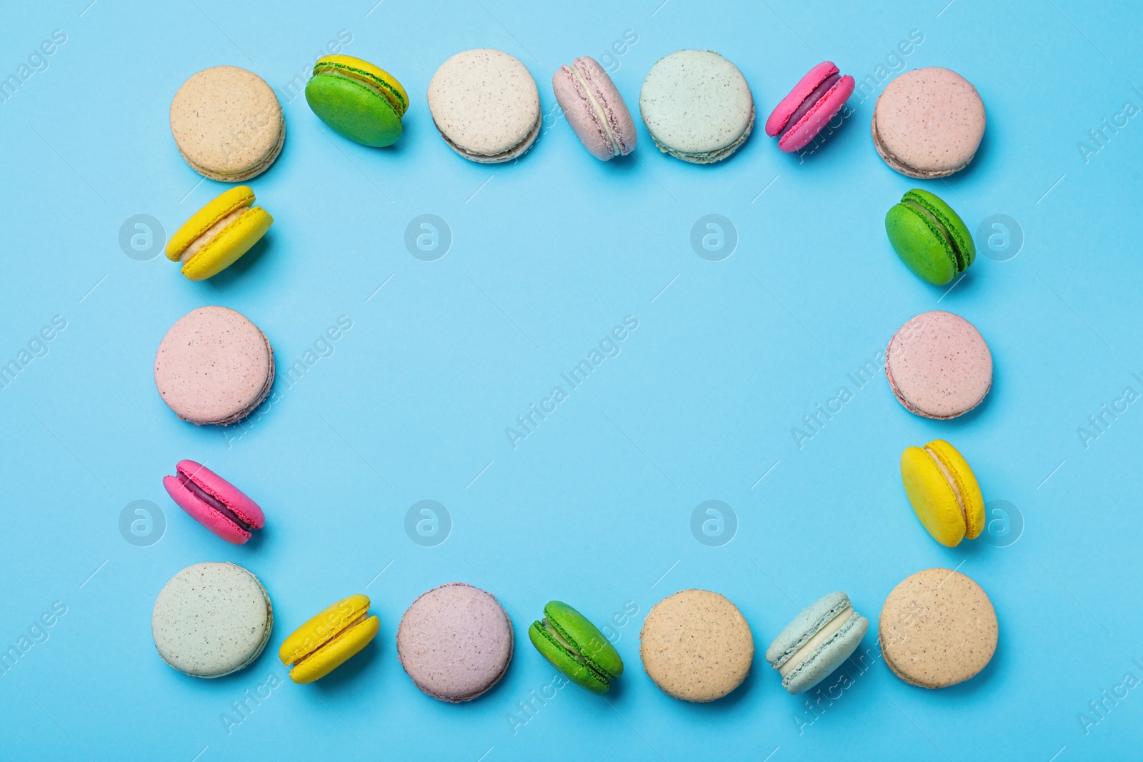 Photo of Frame made of delicious colorful macarons on light blue background, flat lay. Space for text