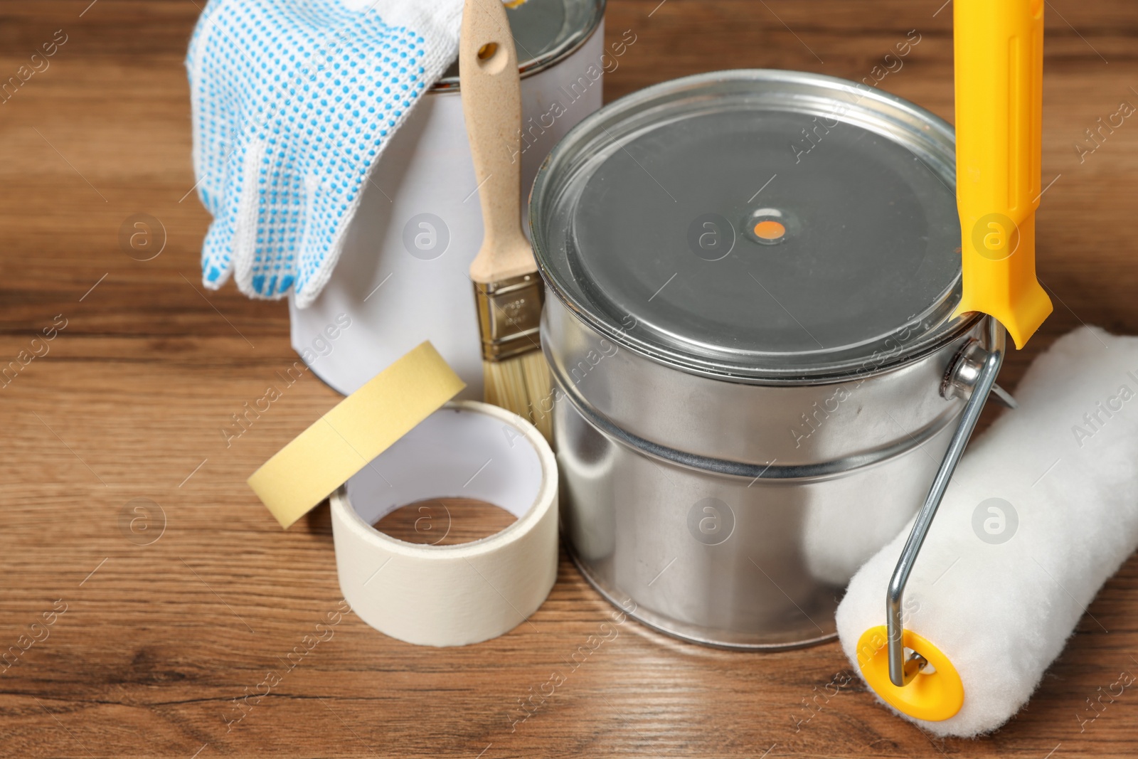 Photo of Cans of orange paint and renovation equipment on wooden table