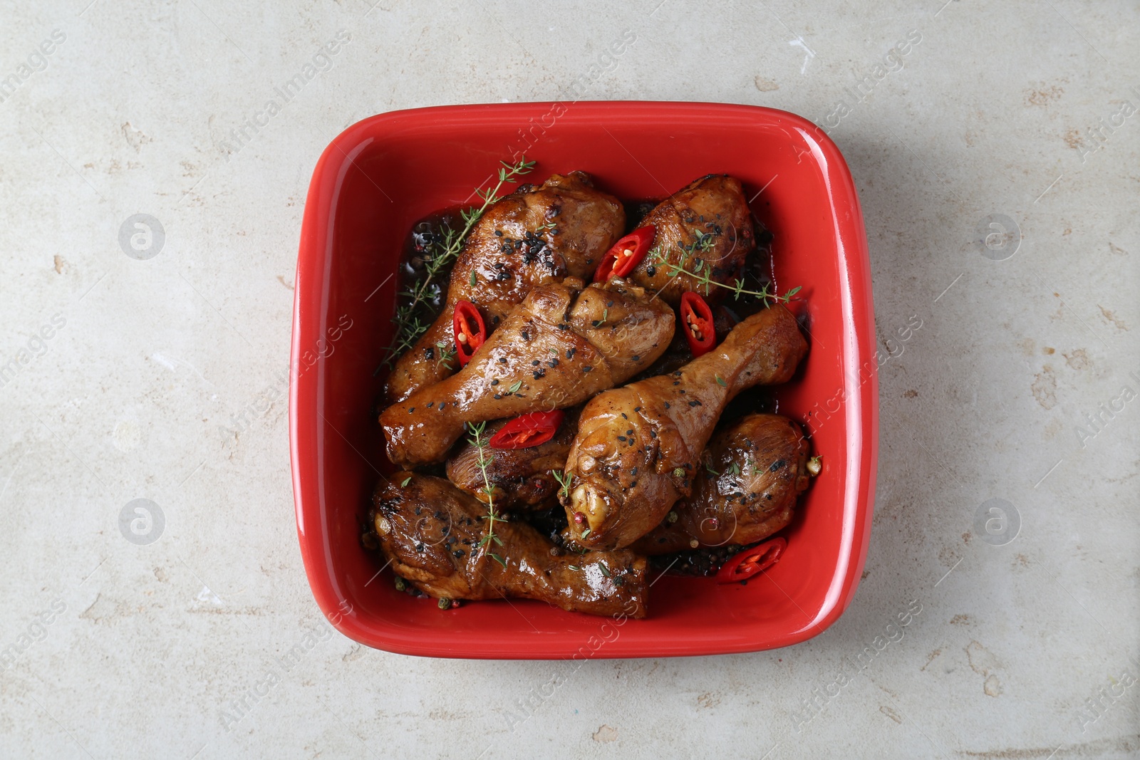 Photo of Chicken legs glazed in soy sauce with black sesame, chili pepper and thyme on light table, top view
