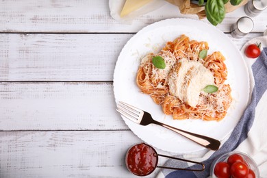 Delicious pasta with tomato sauce, chicken and parmesan cheese on white wooden table, flat lay. Space for text