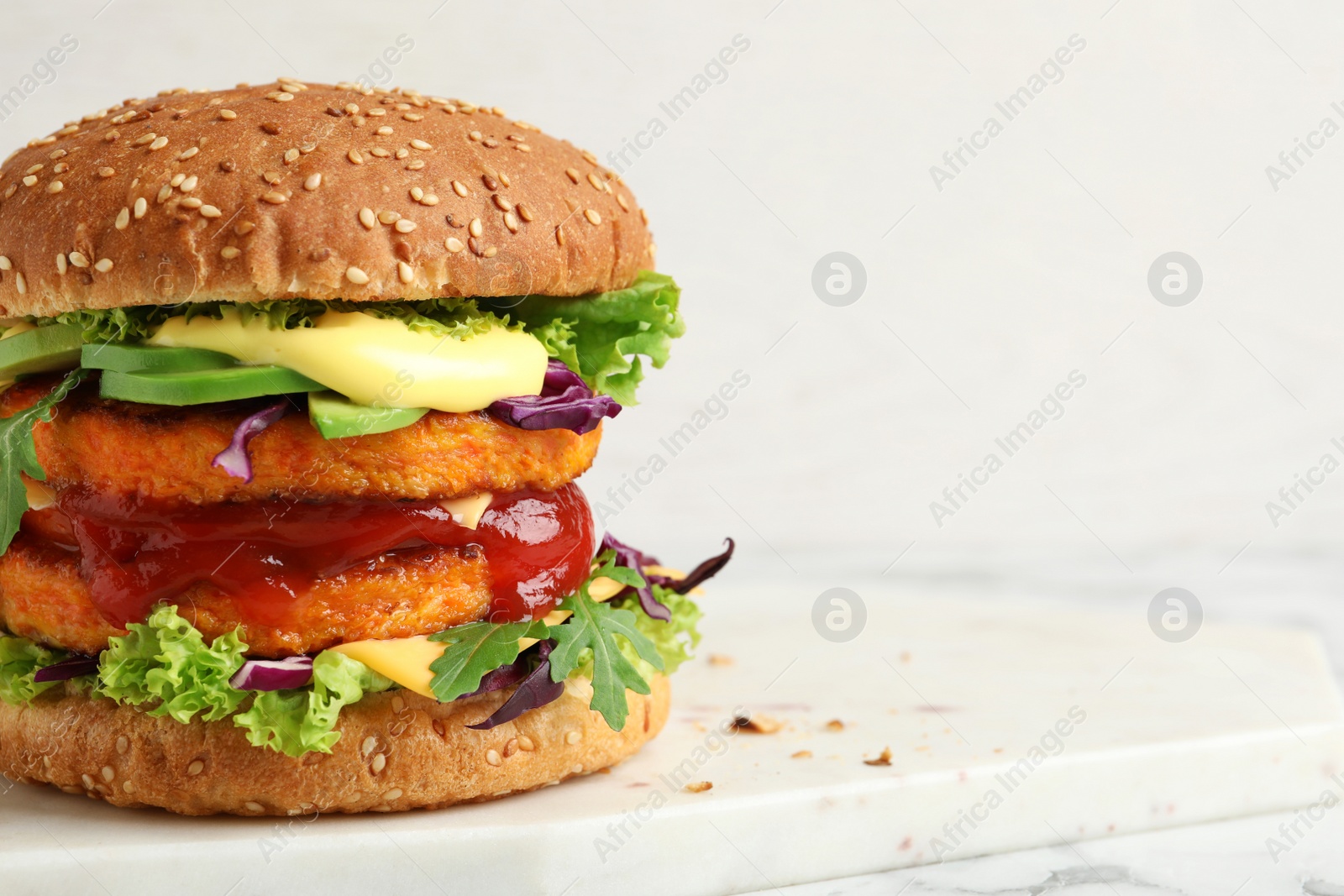 Photo of Vegan burger with carrot patties served on table against light background. Space for text