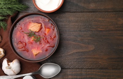 Delicious borscht, garlic and sour cream on wooden table, flat lay. Space for text