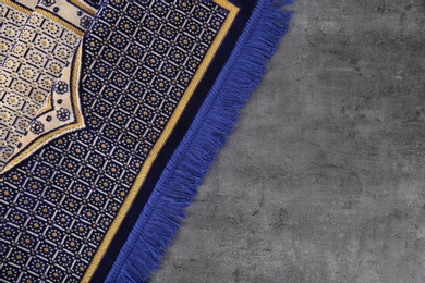 Muslim prayer rug and space for text on grey background, top view