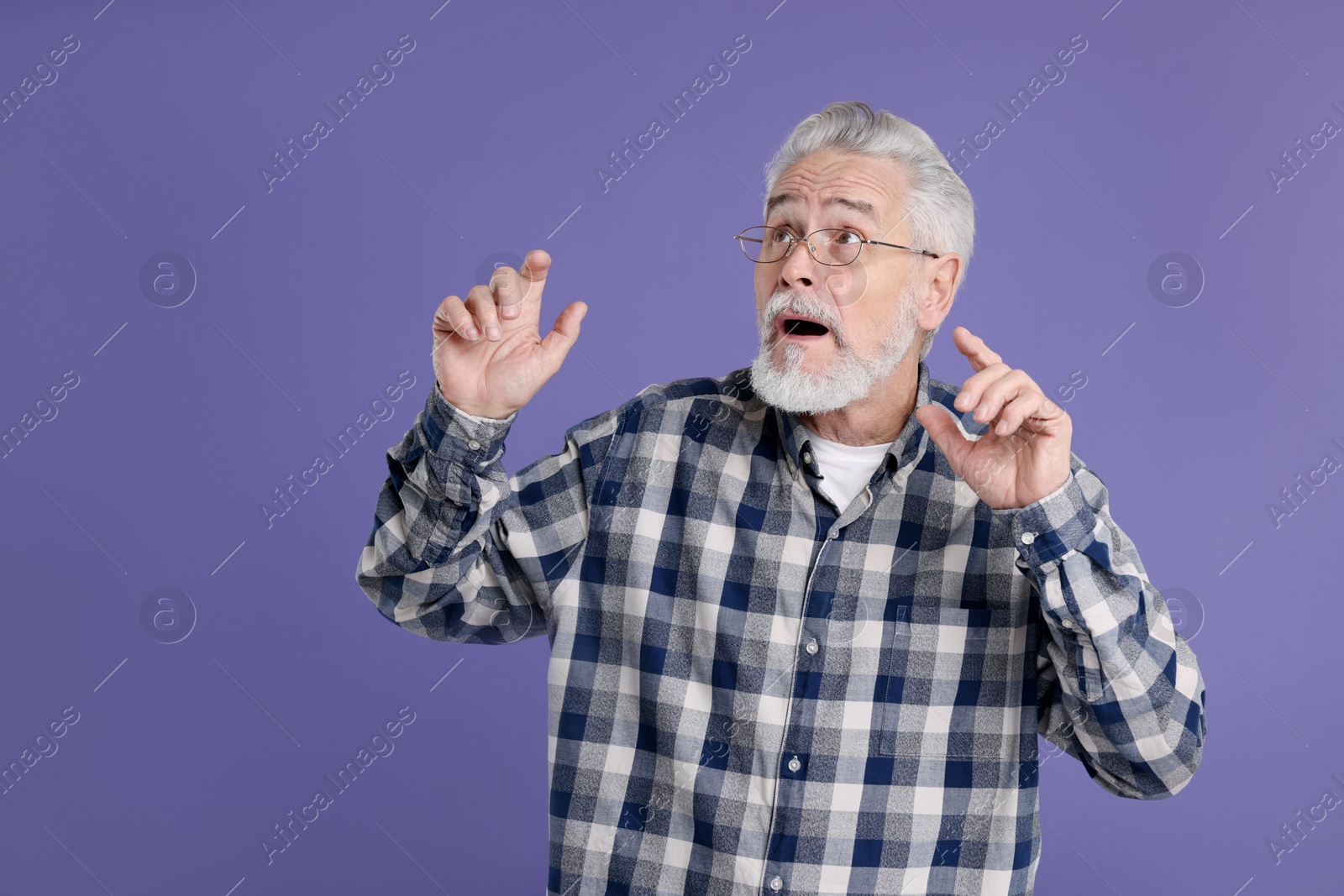 Photo of Portrait of surprised senior man on violet background, space for text