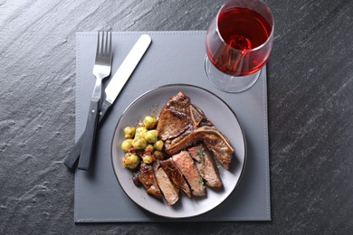 Photo of Delicious fried beef meat and vegetables served on black table, top view