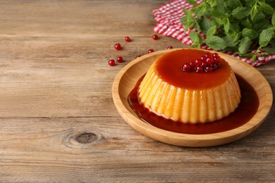 Photo of Delicious pudding with caramel and redcurrants on wooden table. Space for text