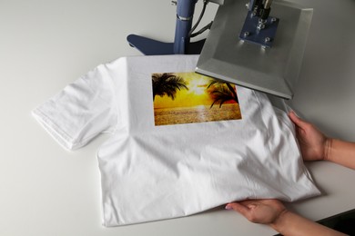 Image of Custom t-shirt. Woman using heat press to print beautiful image of tropical seascape