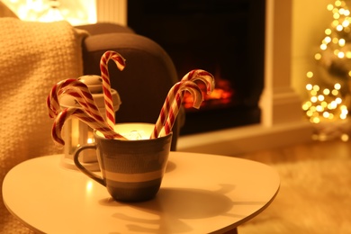 Photo of Christmas candy canes on table in room with fireplace