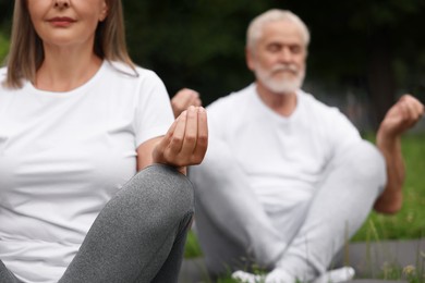 Senior couple practicing yoga outdoors, selective focus