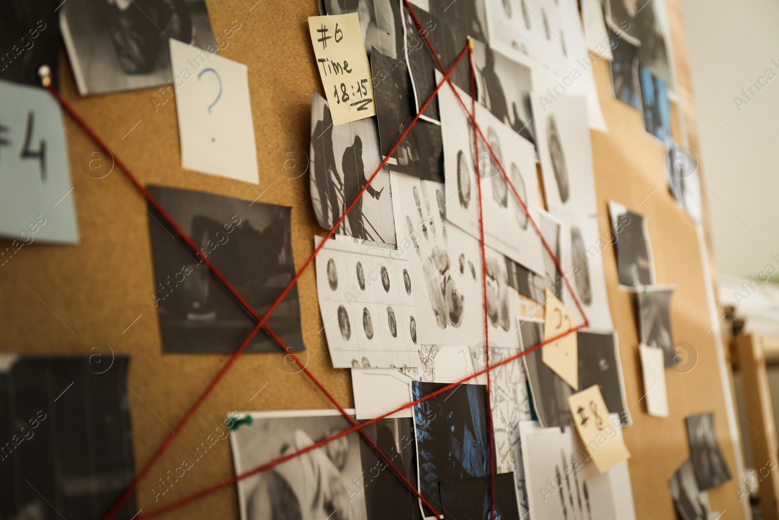 Photo of Detective board with crime scene photos, stickers, clues and red thread, closeup