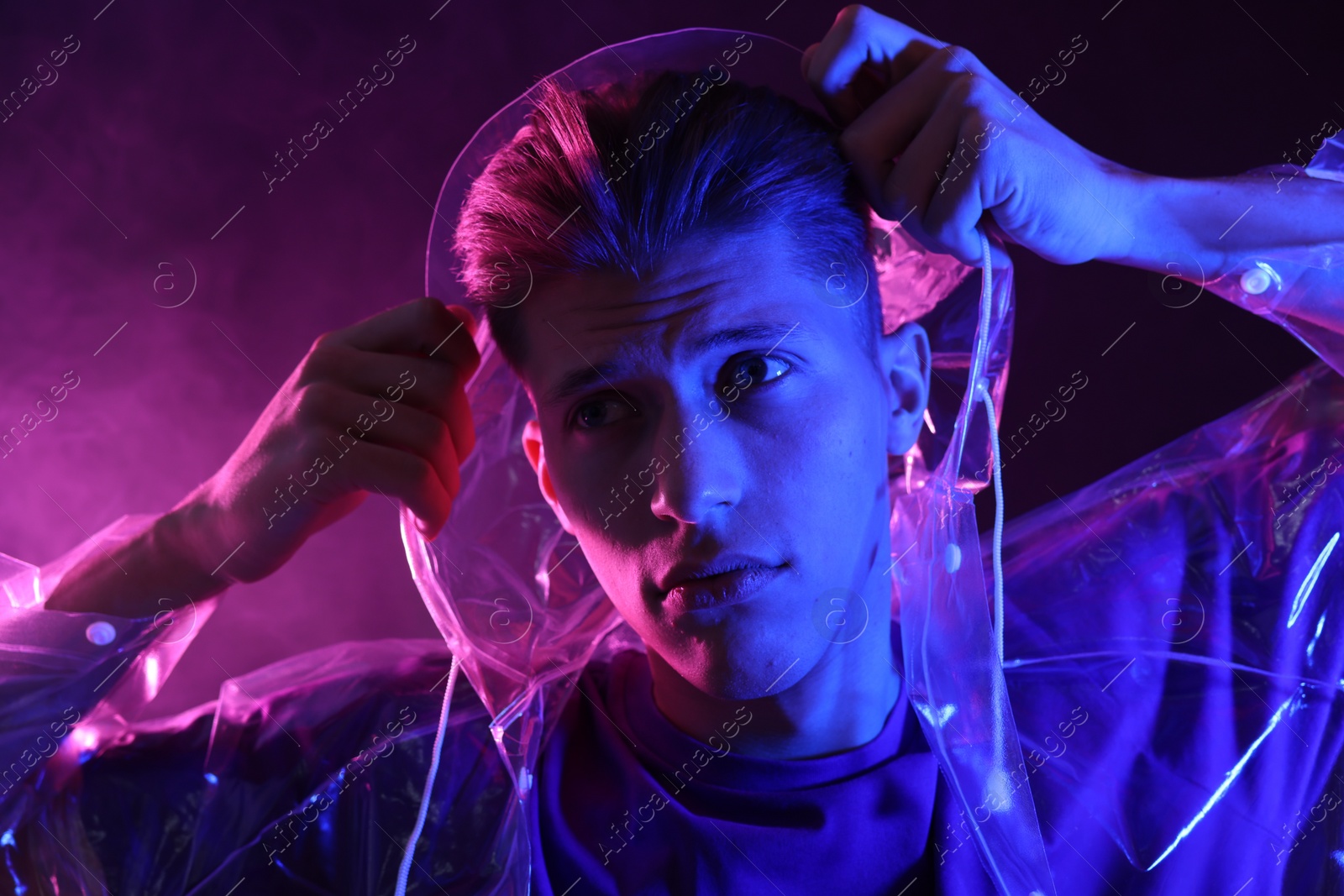 Photo of Young man wearing clear coat in neon lights with smoke effect