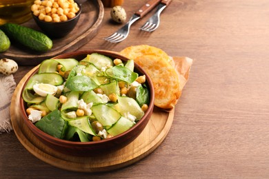 Photo of Delicious cucumber salad and rosted bread served on wooden table. Space for text