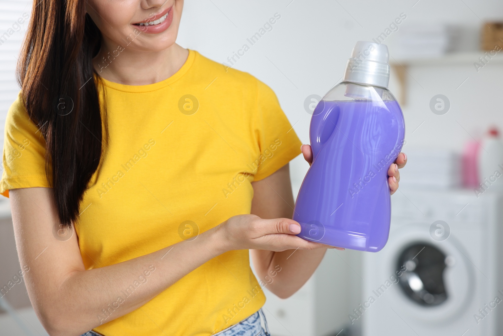 Photo of Woman showing fabric softener in bathroom, closeup