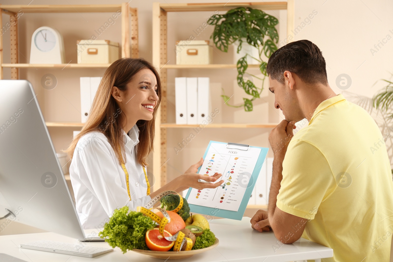 Photo of Young nutritionist consulting patient at table in clinic