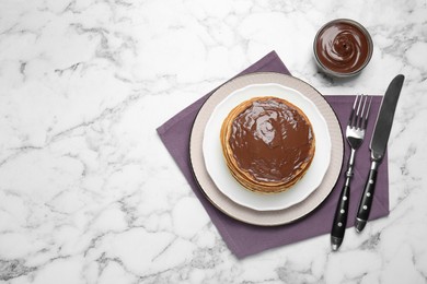 Photo of Tasty pancakes with chocolate paste and cutlery on white marble table, flat lay. Space for text