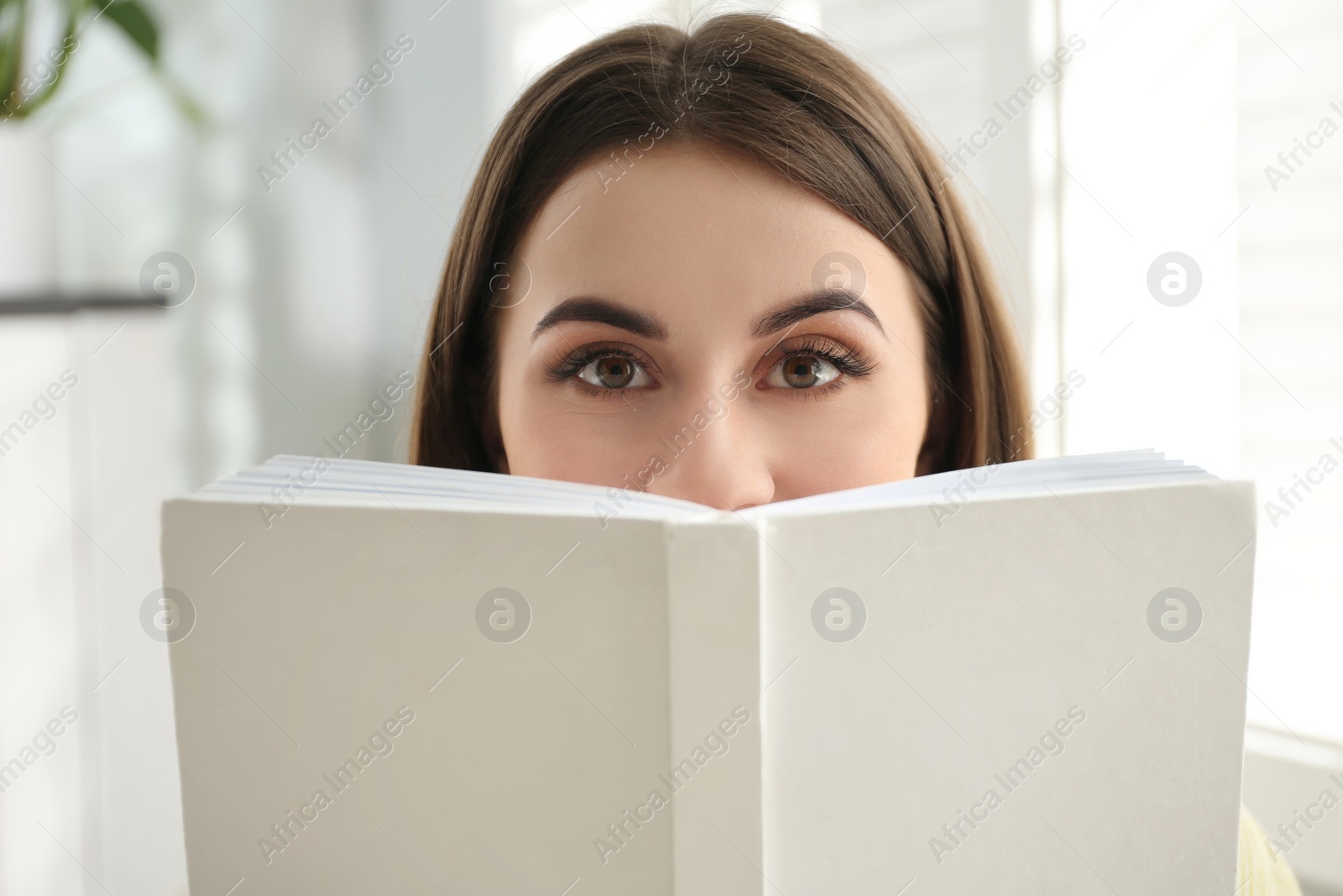 Photo of Beautiful young woman reading book at home