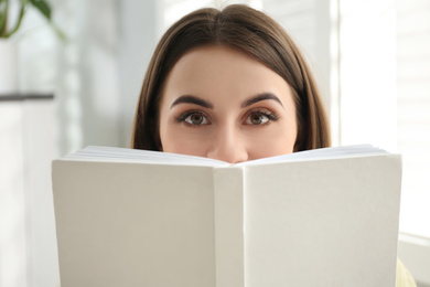 Photo of Beautiful young woman reading book at home