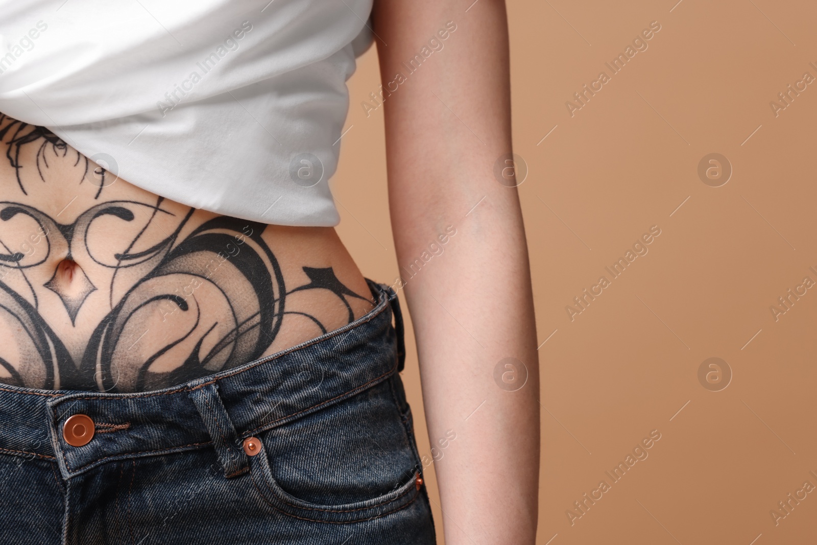 Photo of Woman with cool tattoos on beige background, closeup. Space for text