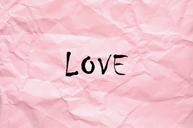 Image of Word Love written on crumpled pink paper, top view