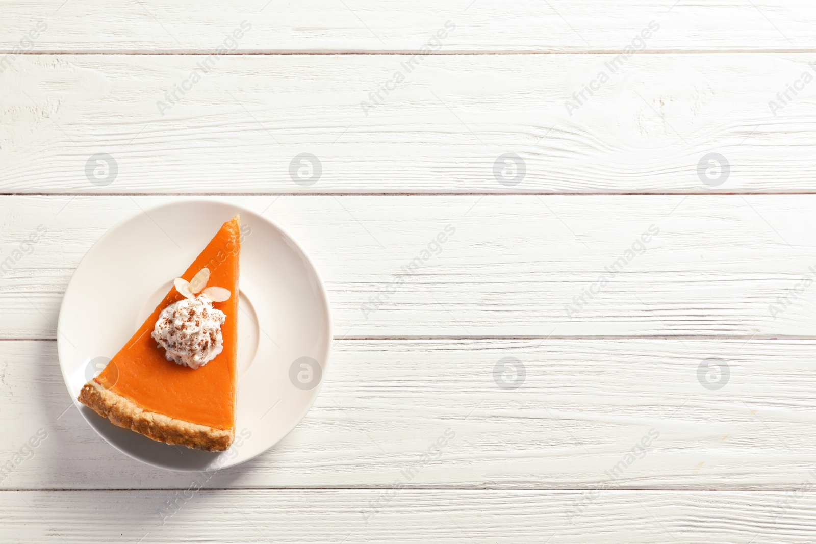 Photo of Plate with piece of fresh delicious homemade pumpkin pie on wooden background, top view. Space for text