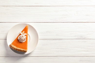 Photo of Plate with piece of fresh delicious homemade pumpkin pie on wooden background, top view. Space for text