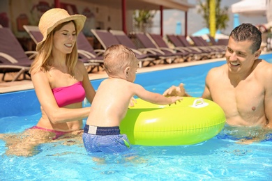 Happy family with little child in swimming pool outdoors