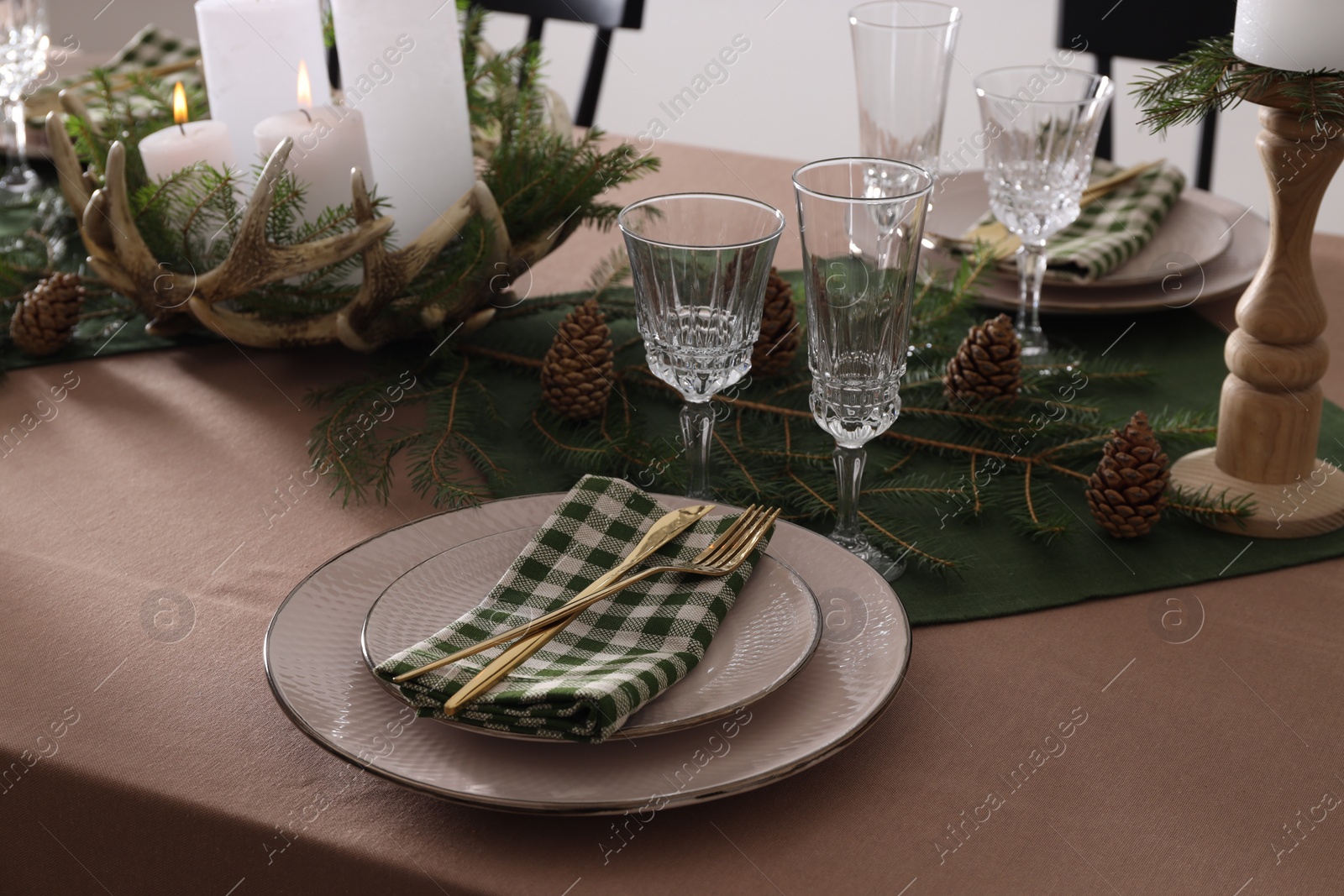 Photo of Christmas table setting with burning candles and other festive decor