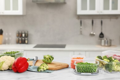 Glass and plastic containers with different fresh products on white marble table in kitchen, space for text