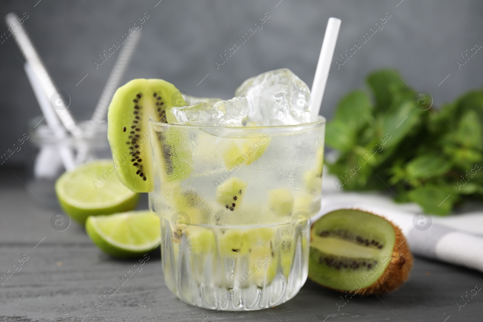 Photo of Glass of refreshing drink and cut kiwi on gray table, closeup