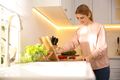 Young woman with tablet cooking at counter in kitchen