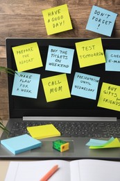 Photo of Many different reminder notes and laptop on table against wooden background