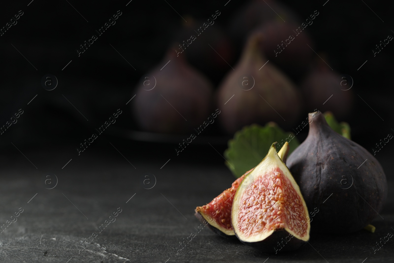 Photo of Tasty raw figs on black slate table, closeup. Space for text