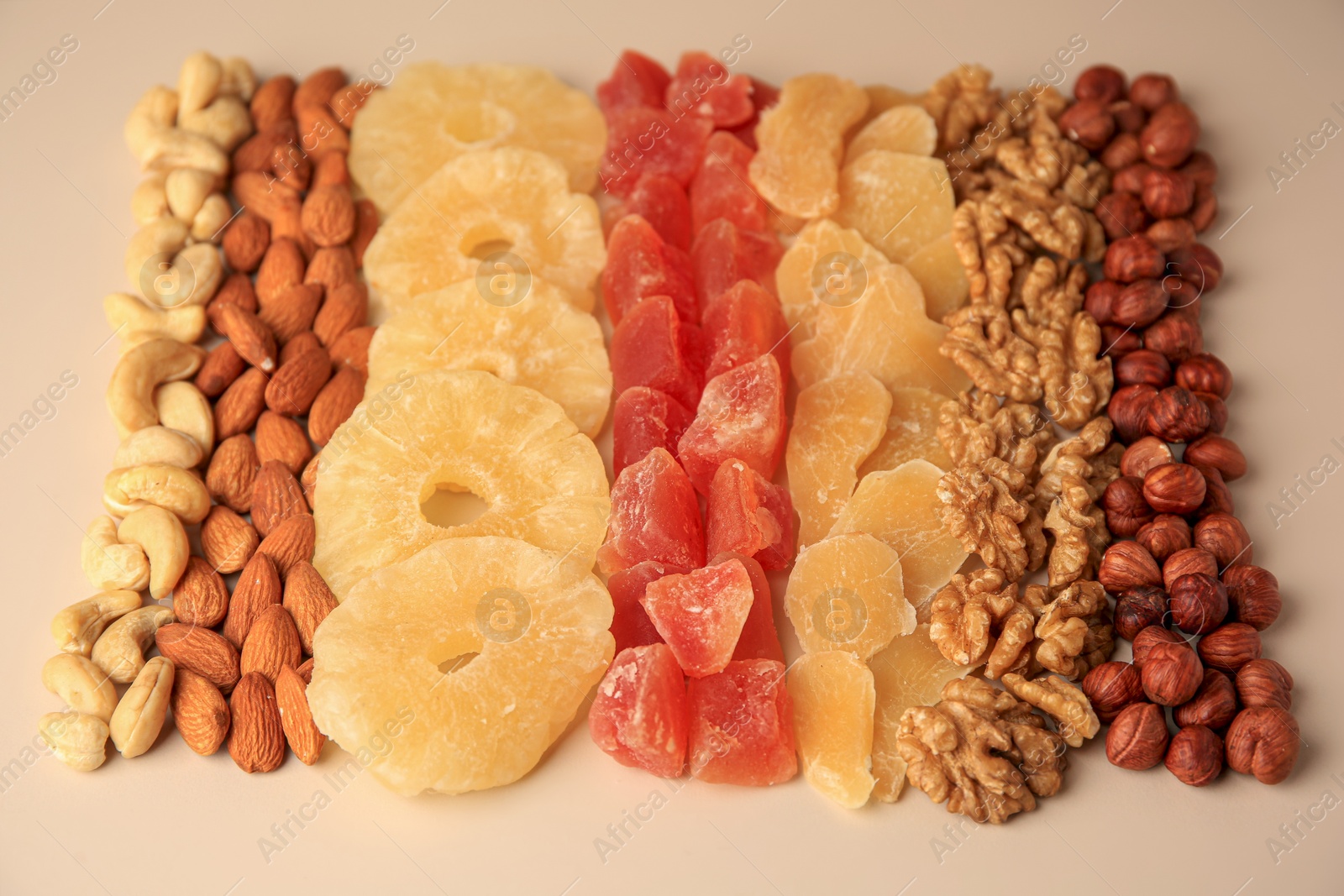 Photo of Different tasty nuts and dried fruits on beige background