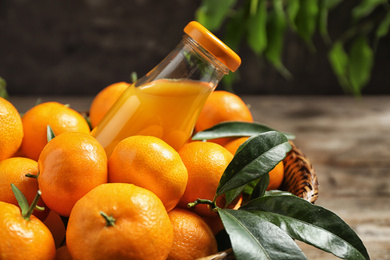 Photo of Basket with fresh tangerines and bottle of juice, closeup