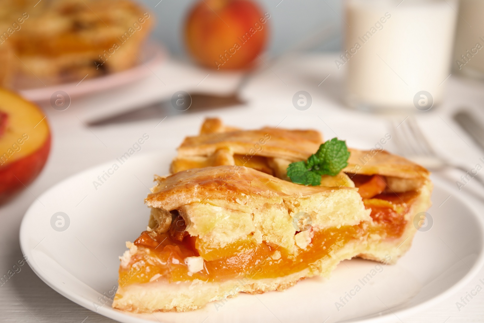 Photo of Piece of delicious fresh peach pie served on white table, closeup