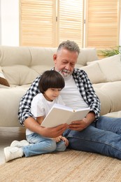 Photo of Happy grandfather with his grandson reading book together at home