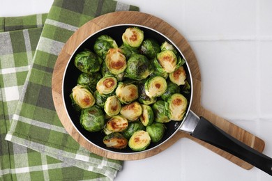 Photo of Delicious roasted Brussels sprouts in frying pan on white tiled table, top view