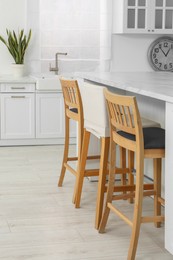 Photo of Stylish white marble table with chairs in kitchen. Interior design