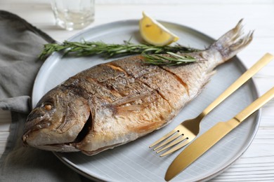 Photo of Delicious baked fish served on white wooden table, closeup. Seafood