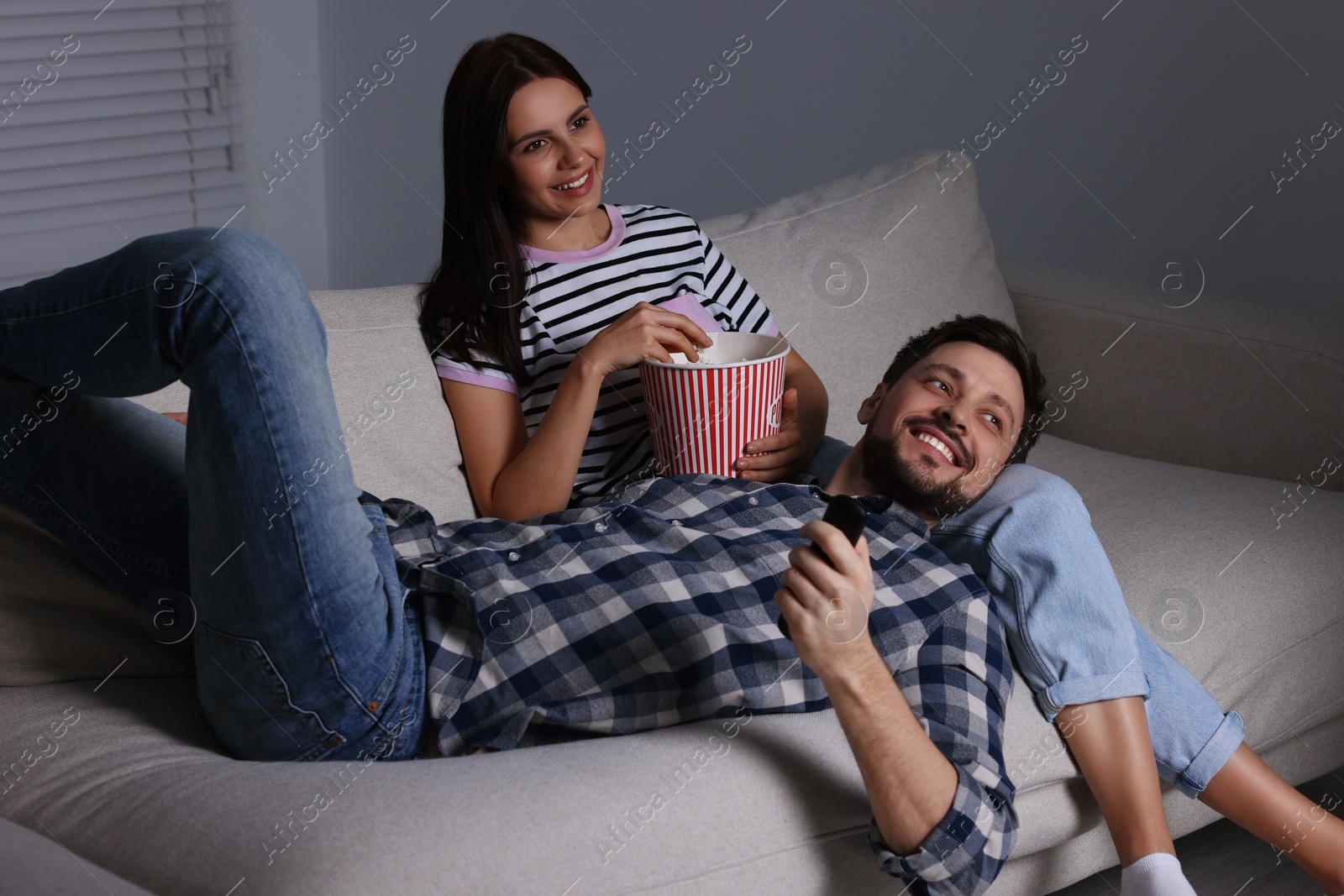 Photo of Happy couple watching TV at home in evening